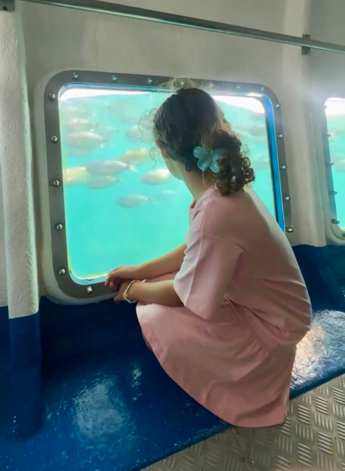 Passagère observant les poissons à travers le hublot en verre du catamaran Nueva Tabarca